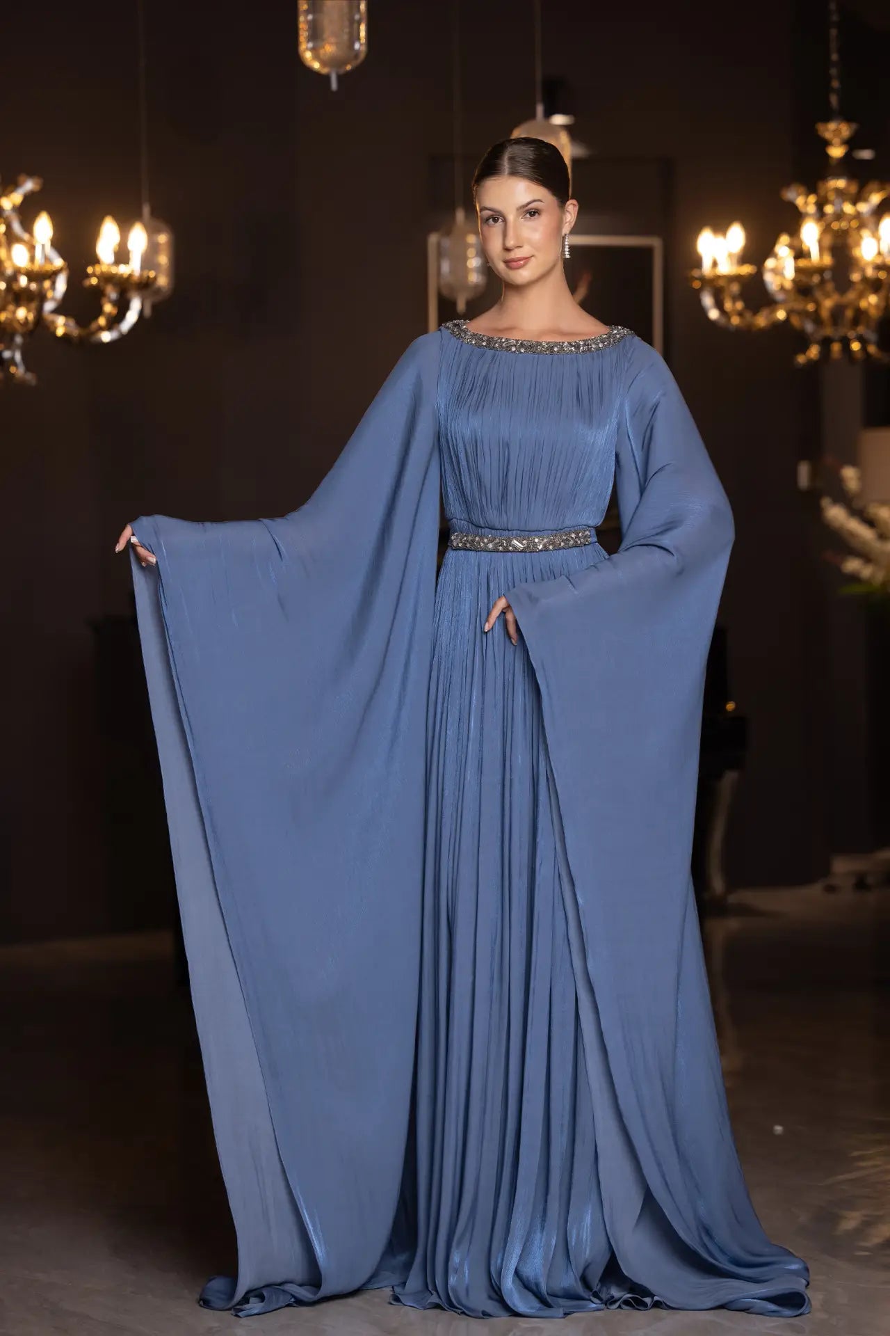 Bloom Dress - Elegant Blue Chiffon with pleated skirt and embellished waist, featuring dramatic cape sleeves for a regal evening look.