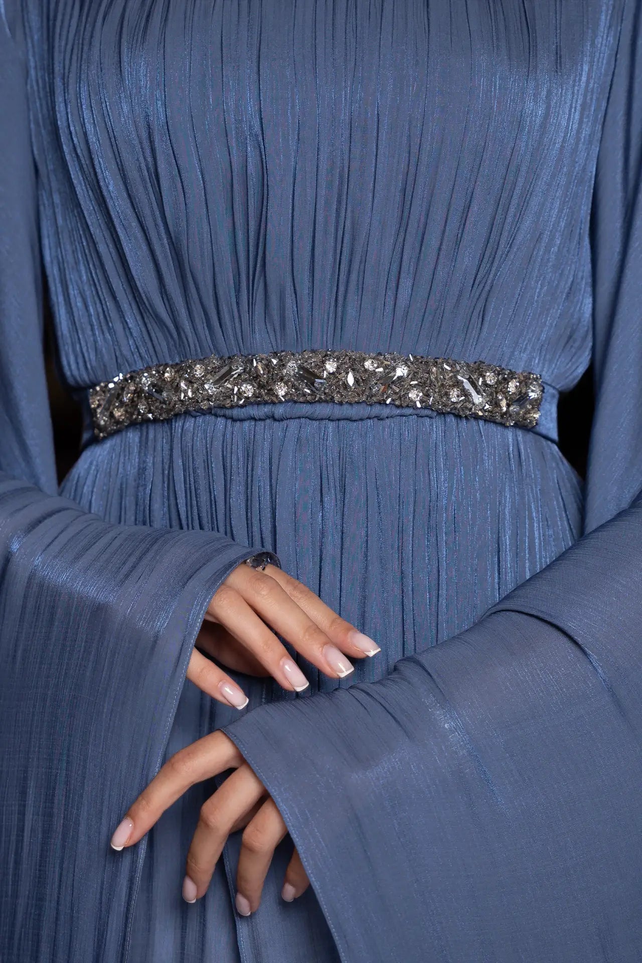 Detail shot of Bloom Dress waistline, featuring ornate silver embellishments on pleated blue chiffon fabric for a refined evening style.