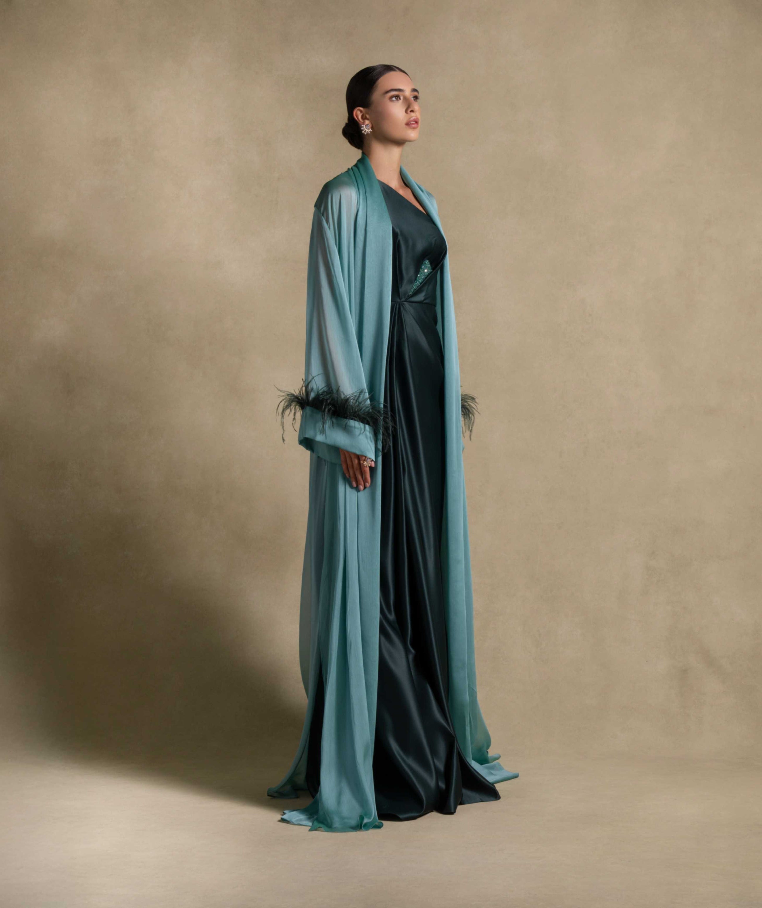 Elegant woman in the Blanche Set featuring a luxurious emerald green gown and feather-trimmed shawl, perfect for high-end fashion events.