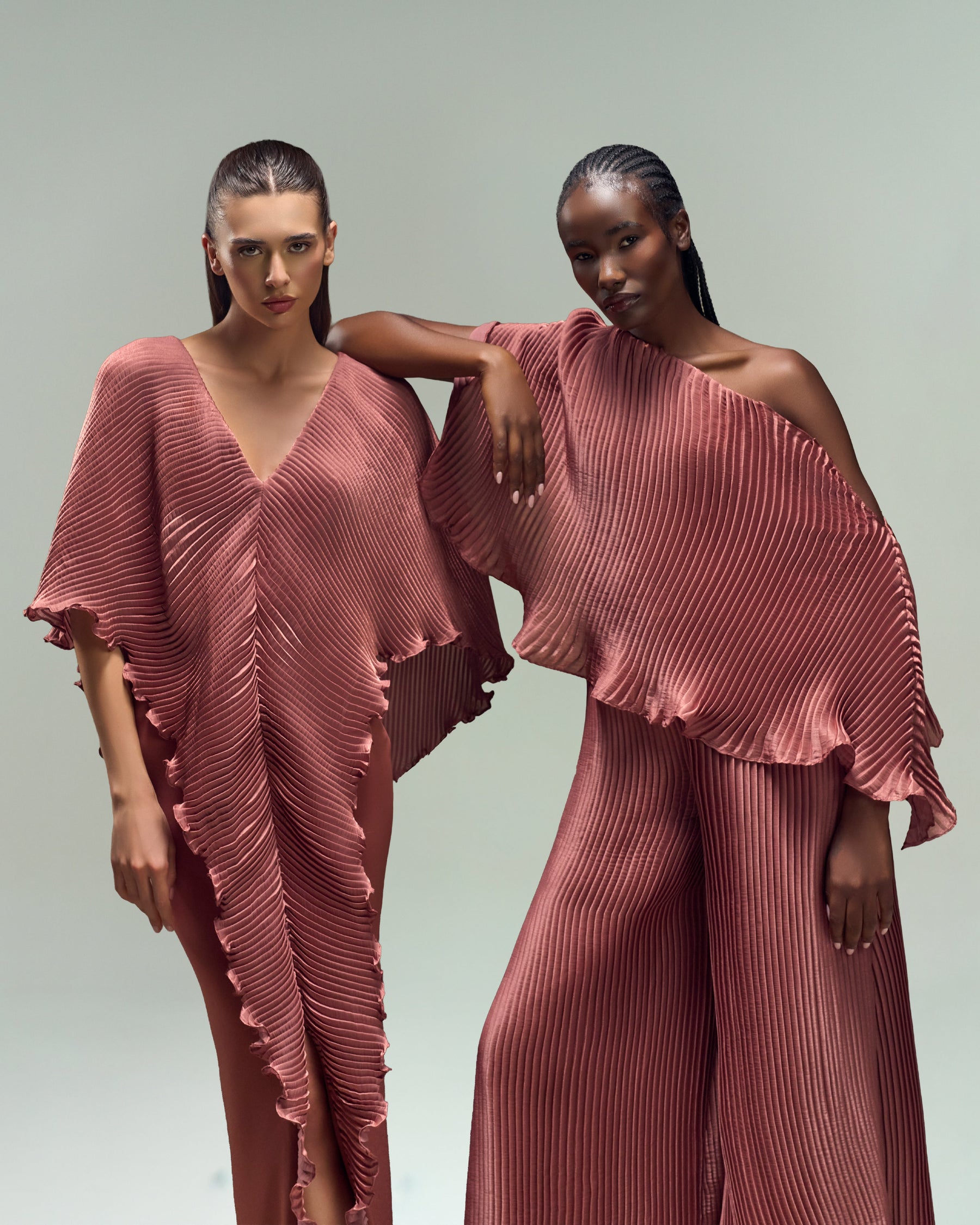 Best selling luxury dresses showcasing two models in chic rust pleated outfits, featuring timeless elegance and modern sophistication.