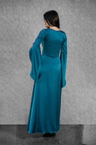 Back view of Solana Dress in teal satin with long flowing skirt and dramatic draped sleeves from the Esperanza Collection AW24.