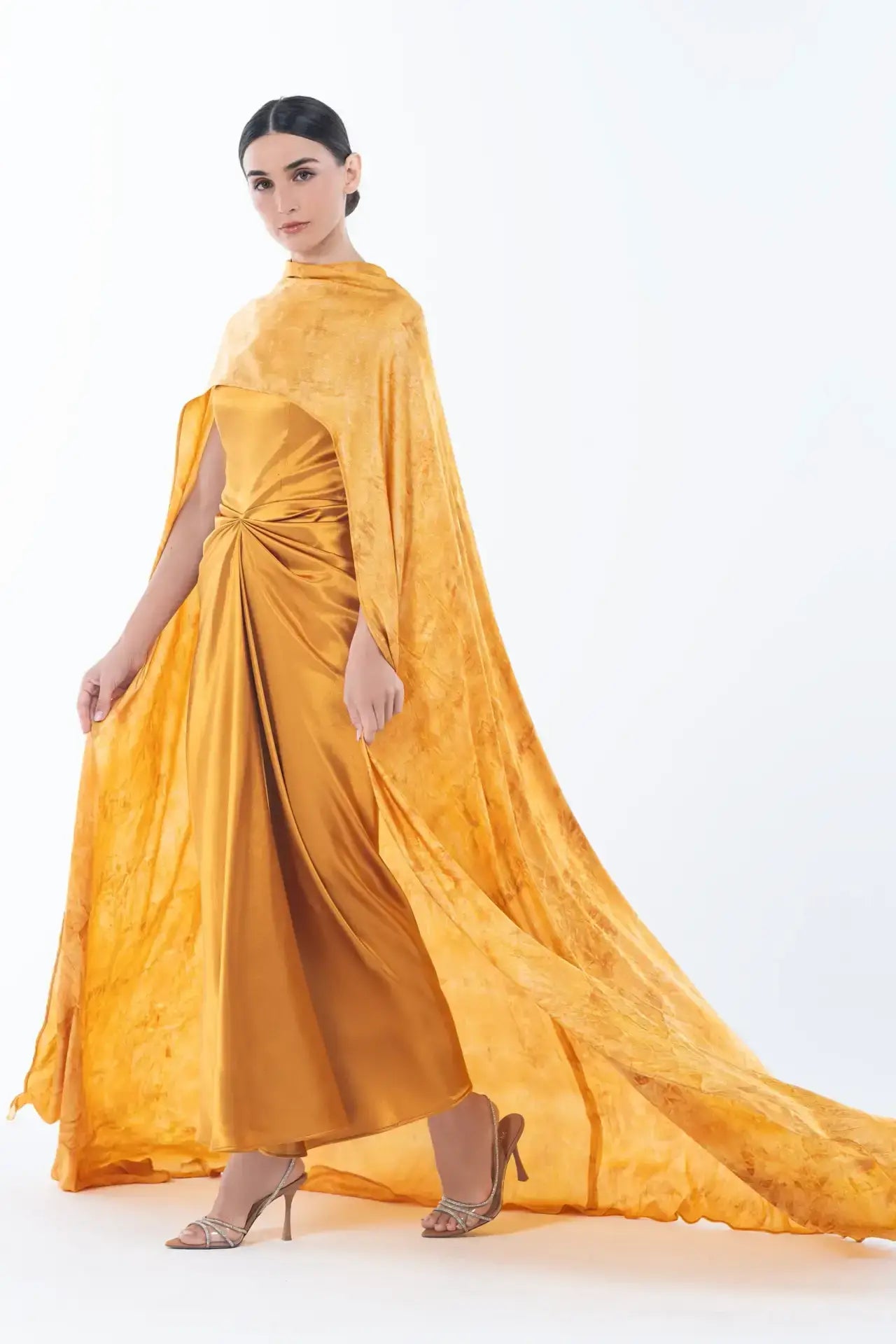 Side view of Helena Dress - Satin Gown | Formal Gown with Cape highlighting the dramatic flowing cape and slim-fit silhouette in mustard satin.