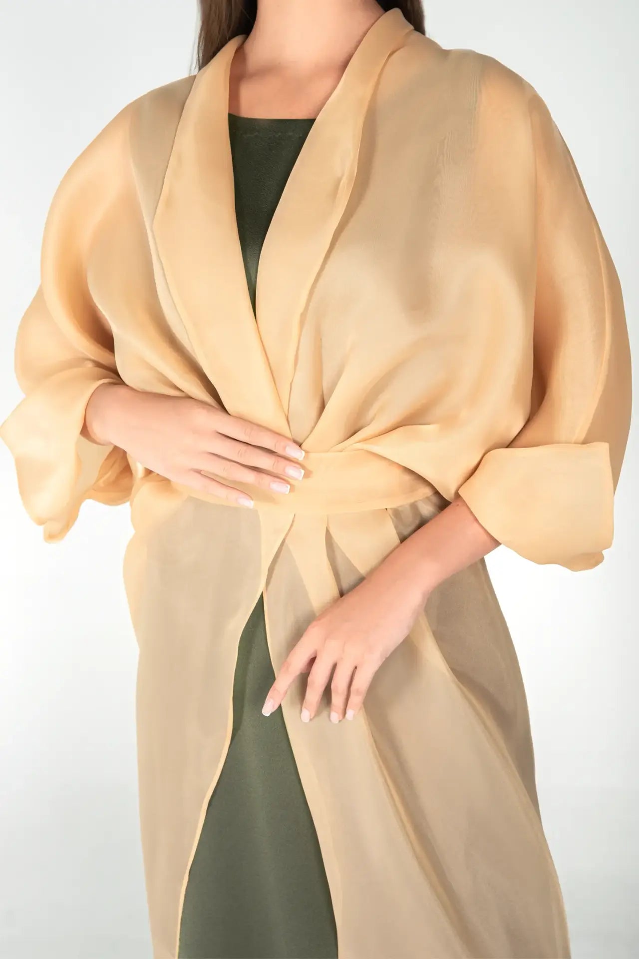 Close-up of Jewel Dress showing sheer organza wrap detail and long sleeves in gold sand, highlighting the luxurious fabric and draping.