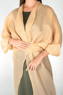 Close-up of Jewel Dress showing sheer organza wrap detail and long sleeves in gold sand, highlighting the luxurious fabric and draping.