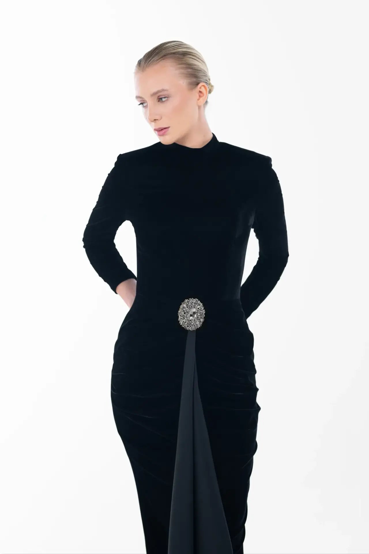 Close-up of Noir Velvet Gown showcasing the high neckline and intricate waist ruching with a statement jeweled brooch.