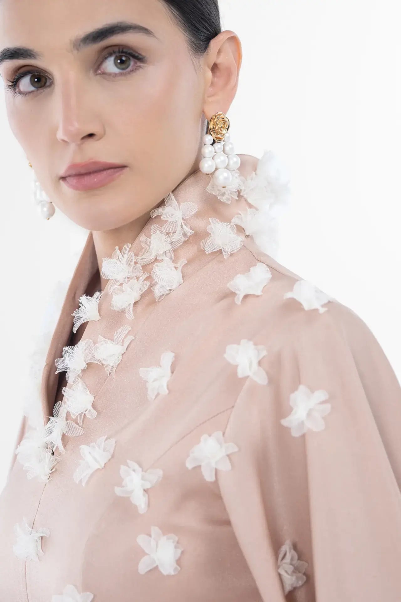 Close-up of Artista Allure Dress collar showing intricate white floral appliqués on blush beige fabric, part of the Ramadan 2025 collection.