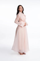 Side view of the Azalea Bella Dress, a soft pink full-length organza gown with elegant drape and wide cuffs, ideal for spring and summer events.
