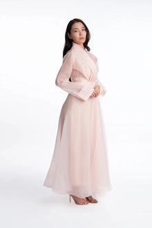 Side view of the Azalea Bella Dress, a soft pink full-length organza gown with elegant drape and wide cuffs, ideal for spring and summer events.