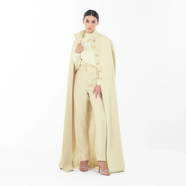 Vuitton Set featuring a high-neck blouse, tailored pants, and a dramatic cape in cream, showcasing luxury women's evening wear.