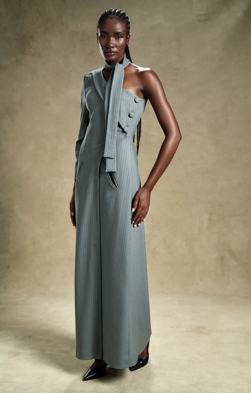 Woman wearing a long, light gray dress with buttons against a beige background