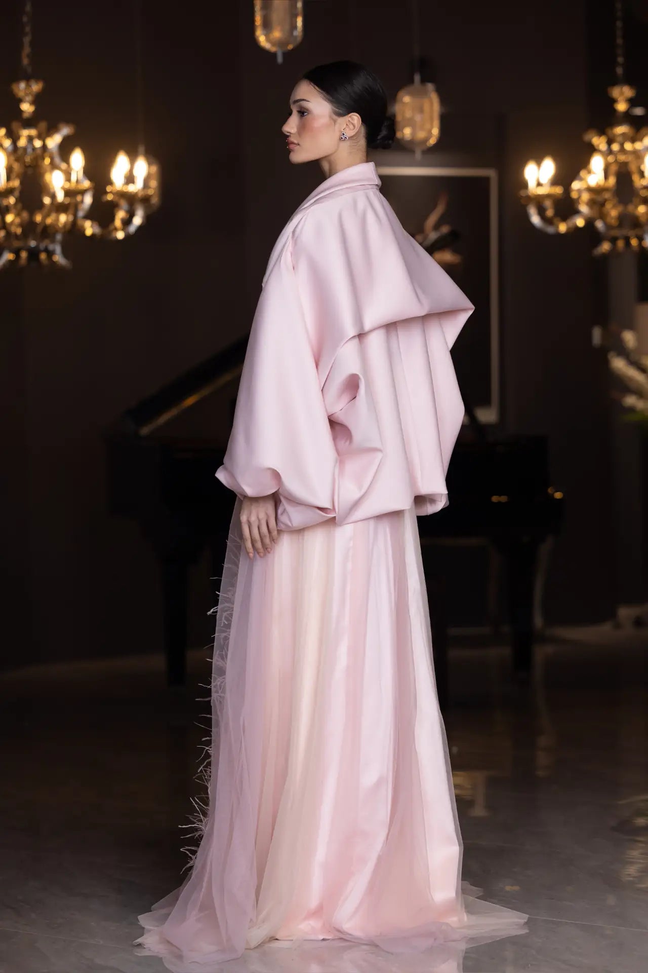 Side profile of Miss Waad Dress - Vérité Majestique showcasing oversized structured cape and flowing tulle skirt in soft pink hues.