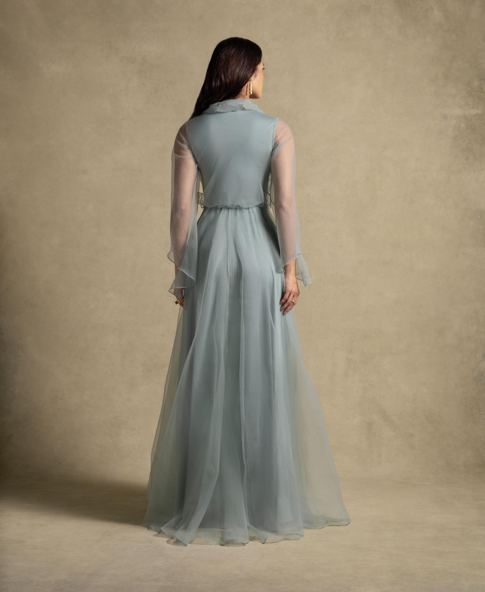 Back view of the Gilded Dress showcasing sage green flowing silhouette and sheer organza sleeves, perfect for evening wear.