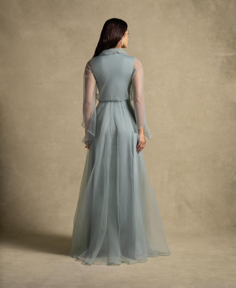 Back view of the Gilded Dress showcasing sage green flowing silhouette and sheer organza sleeves, perfect for evening wear.