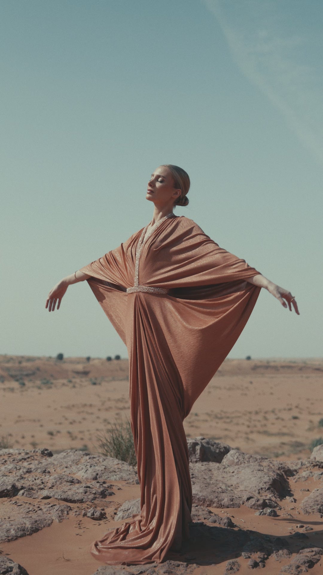Woman in a stunning Moon Set gown from the Zarina Collection, showcasing high-end fashion in a desert landscape.