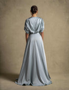 Back view of the Cyra Dress, a luxury sage green maxi dress with soft volume sleeves and elegant drape.