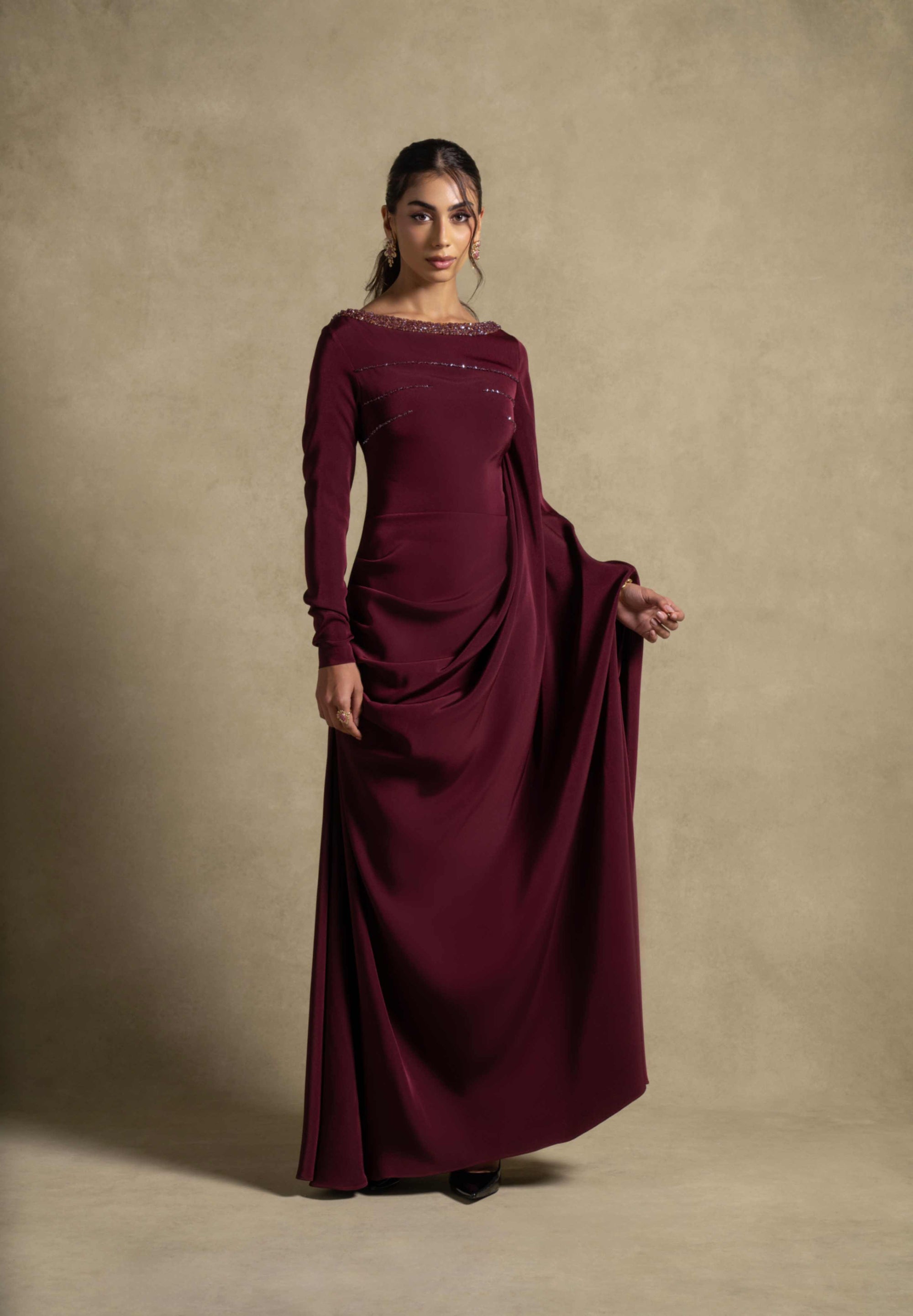 Roxana Dress in maroon from the Zarina Collection, featuring elegant draped detailing and embellished neckline for evening wear.