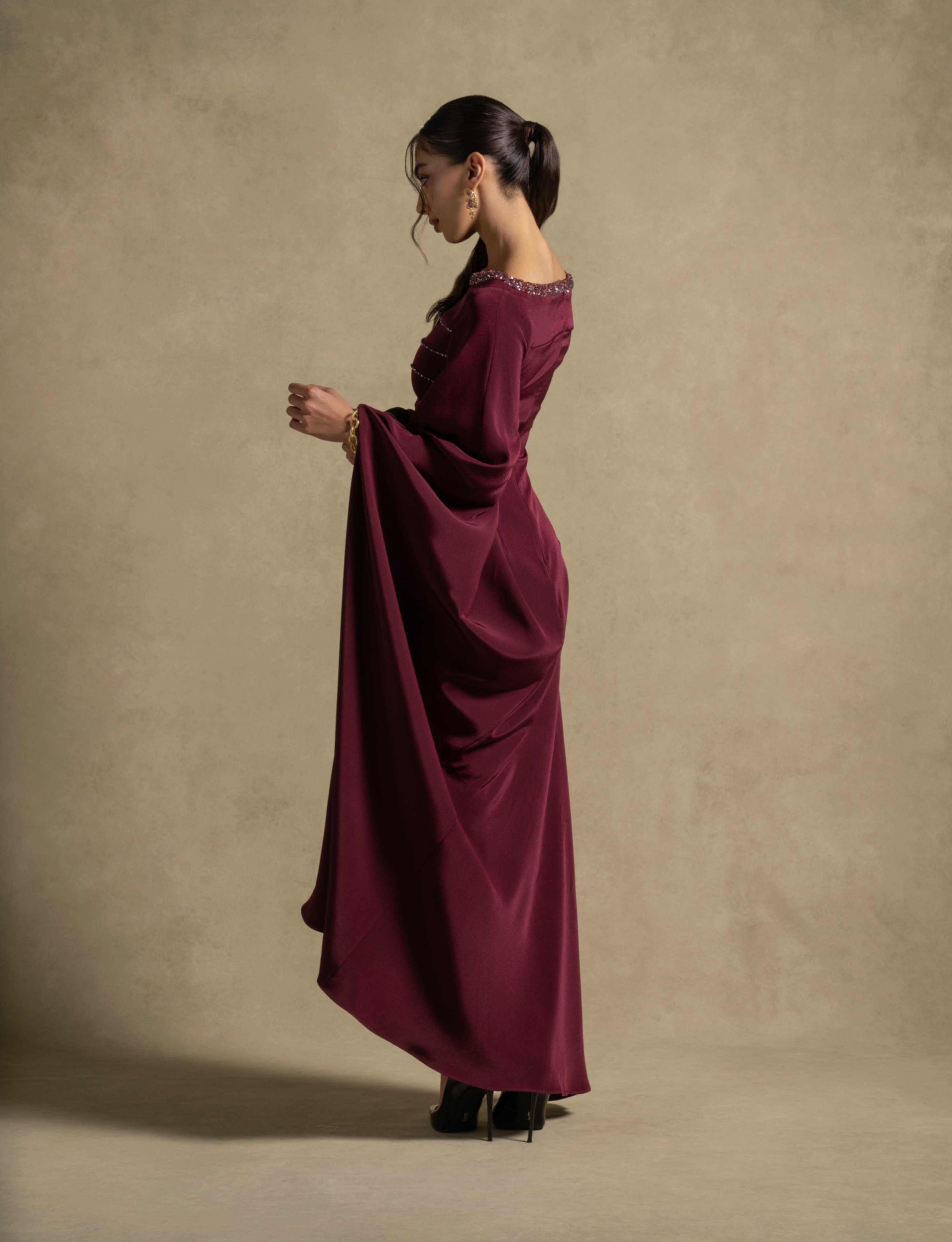 Roxana Dress side view in maroon, showcasing elegant draped detailing and embellished neckline, perfect for evening wear.
