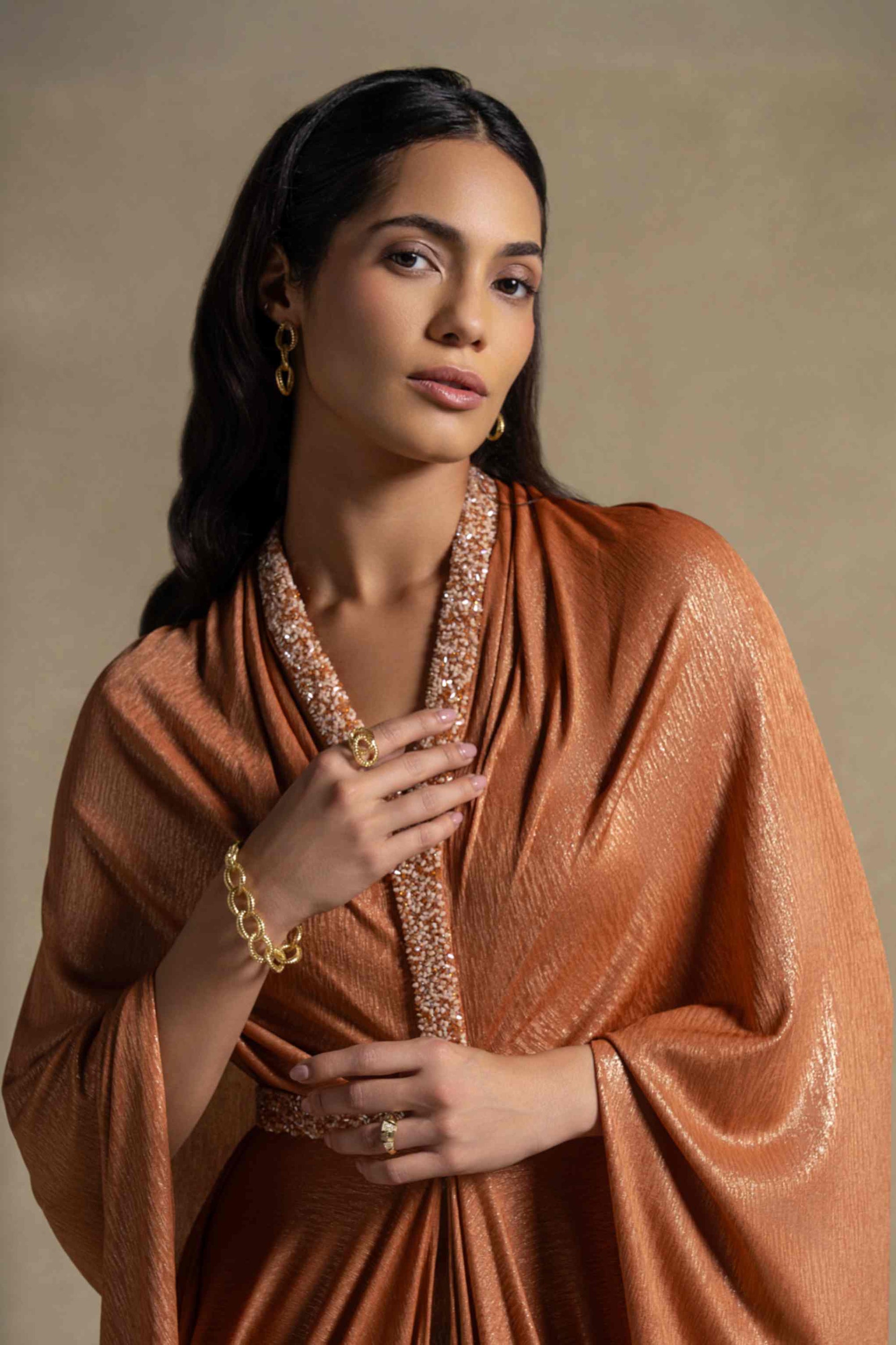 Woman wearing the Moon Set Isabeau gown in radiant Tangerine with elegant accessories, showcasing luxury fashion.