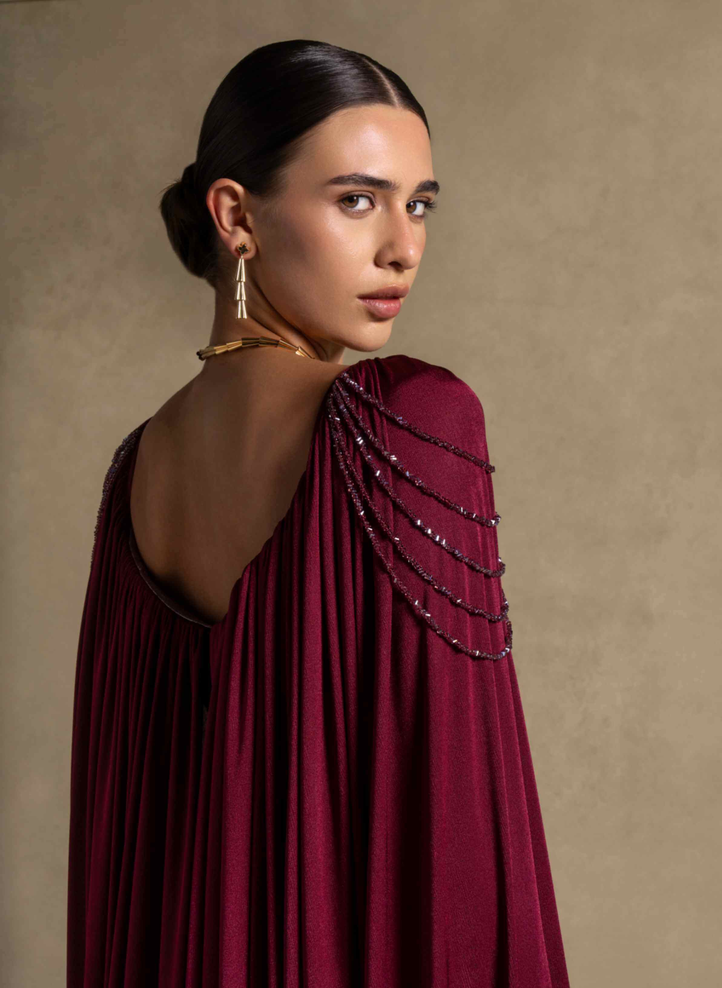 Vionna Dress features a deep Maroon color, beaded shoulder accents, and draped jersey panels for luxury evening wear.